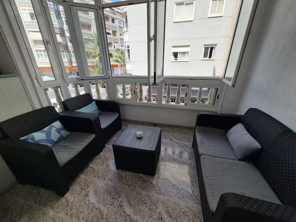 Glazed balcony with two armchairs, a sofa and a low table